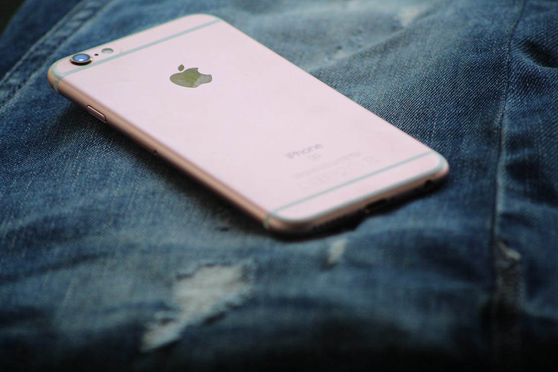 玫瑰金iphone 6s在蓝色牛仔牛仔裤上的特写摄影 免费素材图片