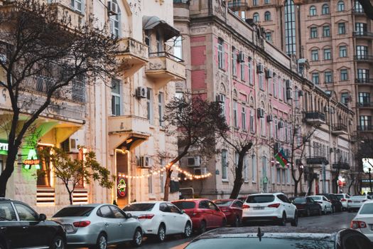 Charming urban street scene featuring historic architecture and parked cars in a lively downtown area.