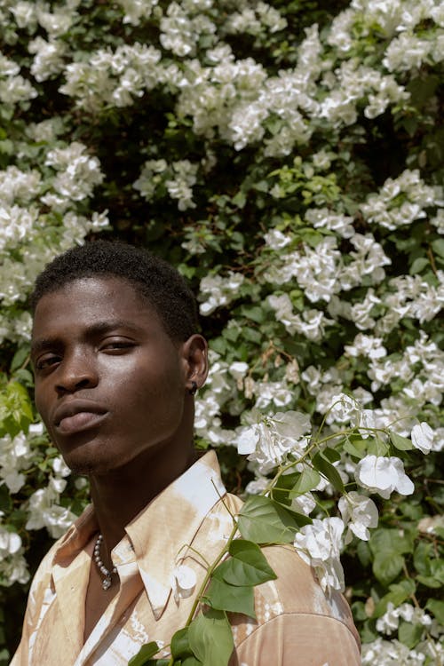 Man Looking at The Camera in Front of White Flowers