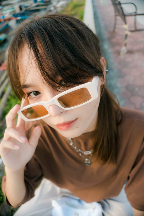 Pretty Woman in Brown Shirt with Sunglasses Looking at Camera