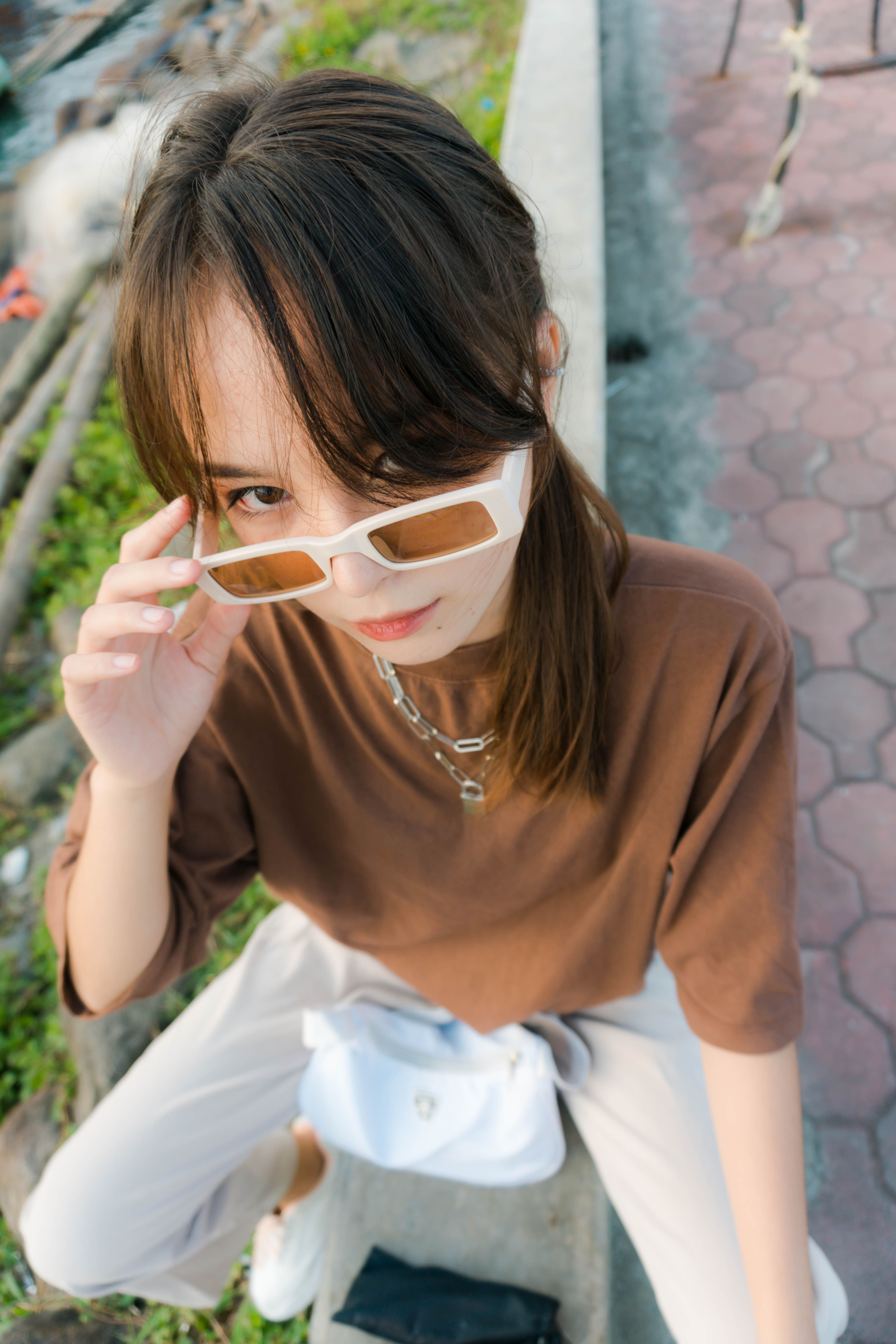 A fashionable young woman striking a pose outdoors with bold sunglasses.