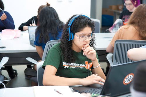 Woman Wearing Blue Headphones Studying on Her Laptop