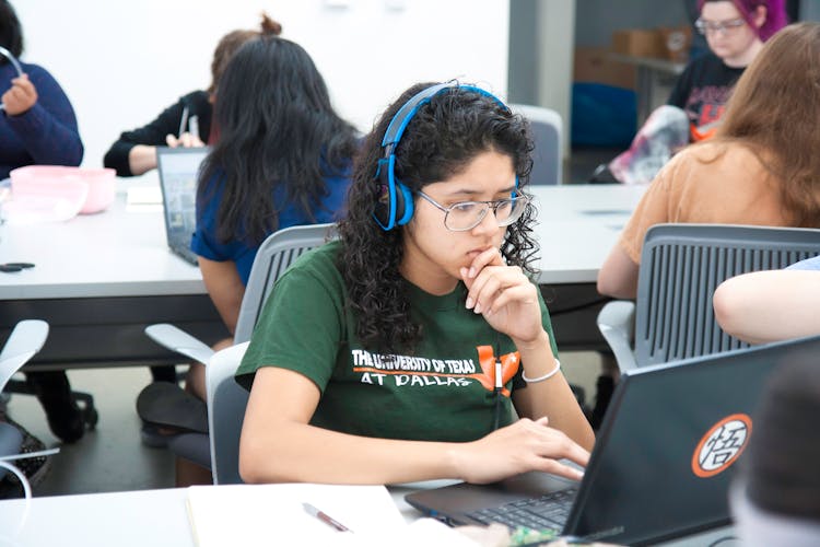 Woman Wearing Blue Headphones Studying On Her Laptop