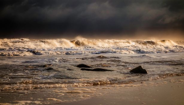 Captivating view of powerful ocean waves crashing on a rugged shoreline under a moody sky.