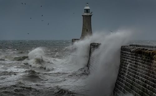 Free Powerful ocean waves crash against a lighthouse, showcasing nature's raw and dramatic force. Stock Photo