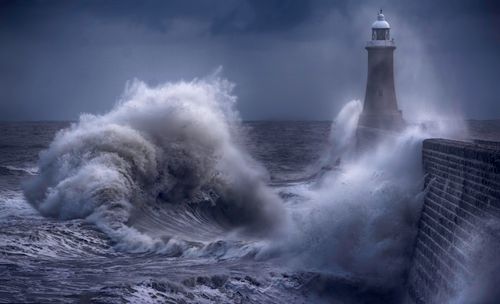 Storm wave breaking beside a lighthouse, photo by Ray Bilcliff on Pexels