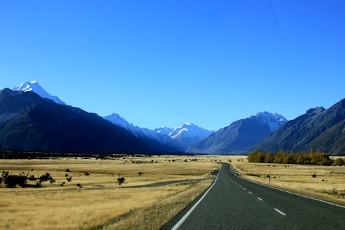 Empty Road Near Mountain Under Blue Skies