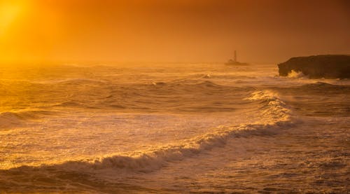 Free Ocean Waves Crashing the Shore during Sunset Stock Photo