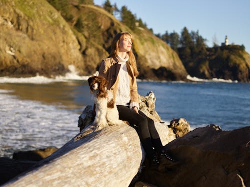 Woman in the Seashore Sitting Beside Her Labradoodle Dog 