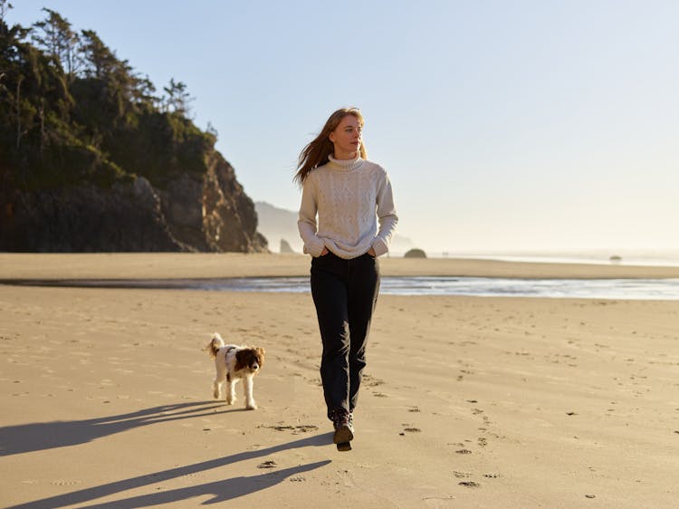 A Dog Following The Woman In The Beach 