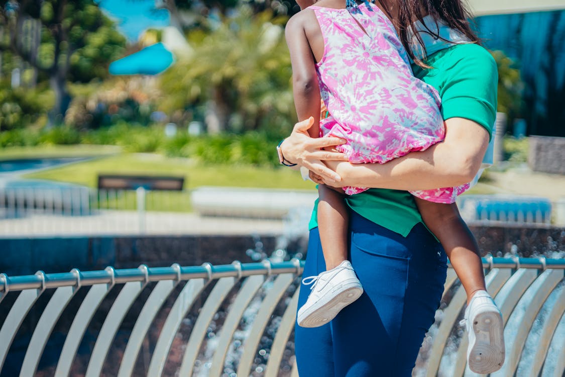 Woman in Pink and White Floral Tank Top and Blue Denim Jeans Holding Pink Plastic Bag