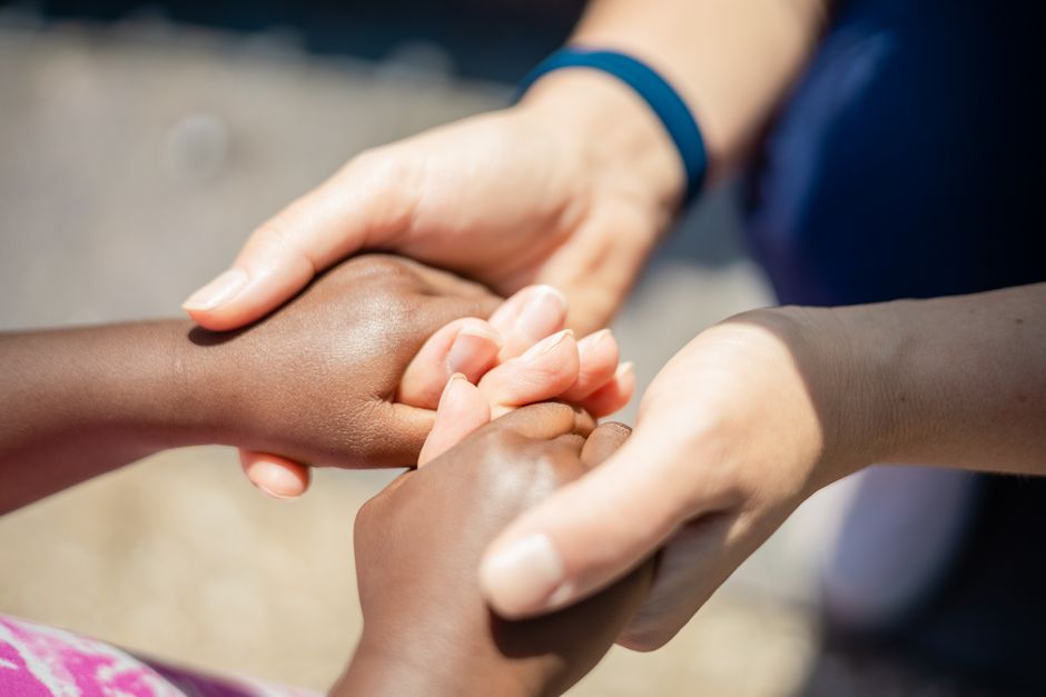 understanding diluted earnings per share - Two pairs of diverse hands holding, symbolizing unity and empathy, close-up outdoor shot.