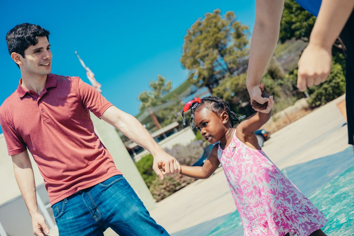 Pai e filha negros de mãos dadas no parque representando vínculo afetivo e pensão socioafetiva