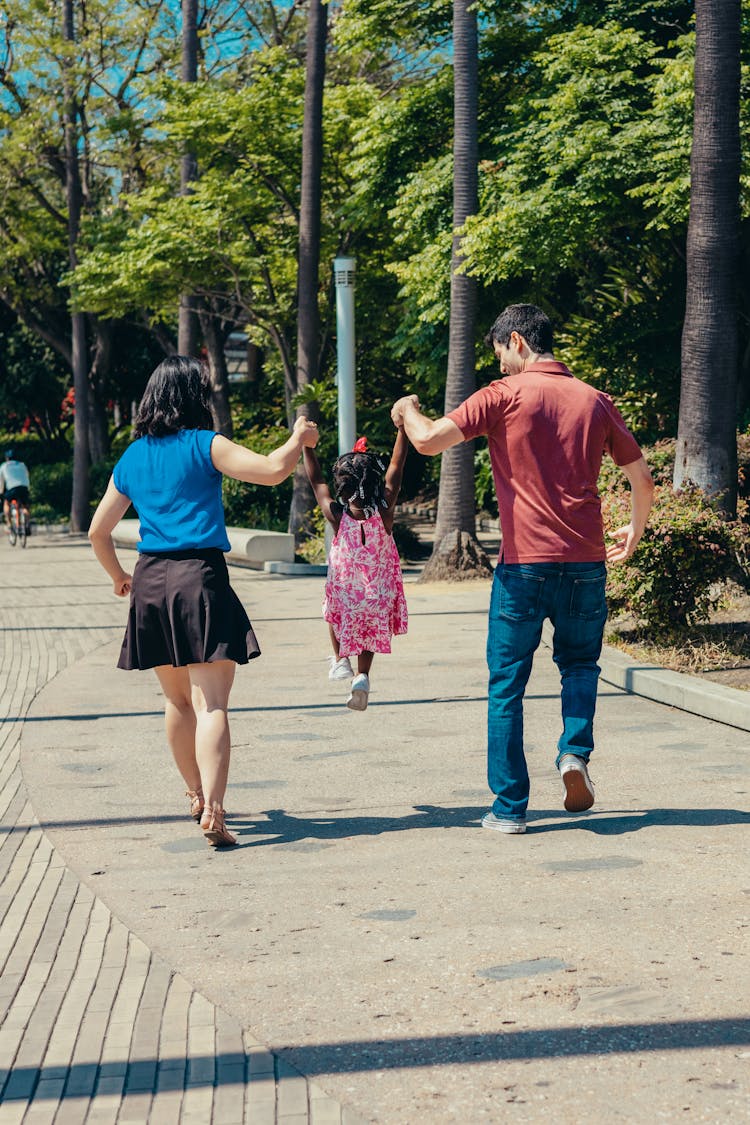 Back View Shot Of A Family Walking On The Park While Holding Each Others Hand