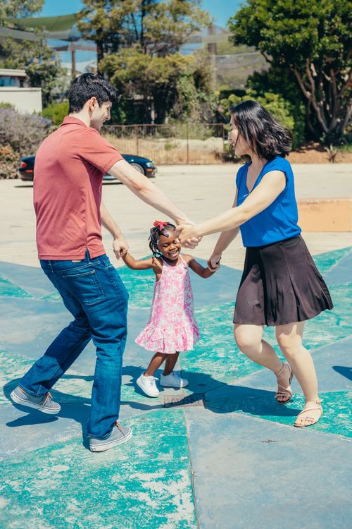 Free A diverse family joyfully playing outdoors in a sunny park setting. Stock Photo