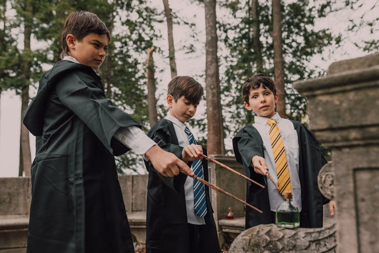 Boys In Black Robes Holding Wands