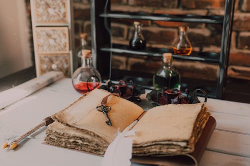 An Old Book and Candles on Wooden Table with Glass Bottles