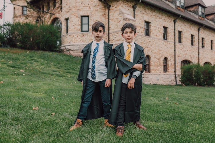 Boys Wearing Black Coats While Standing Near The House With Stone Walls