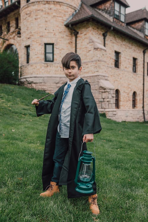 A Boy in Black Robe Holding a Lamp and a Wand