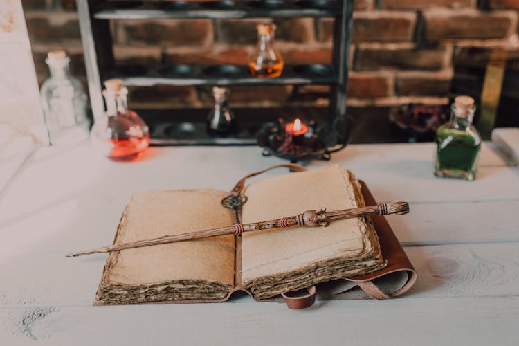 Close-Up Shot Of A Spell Book And A Wand