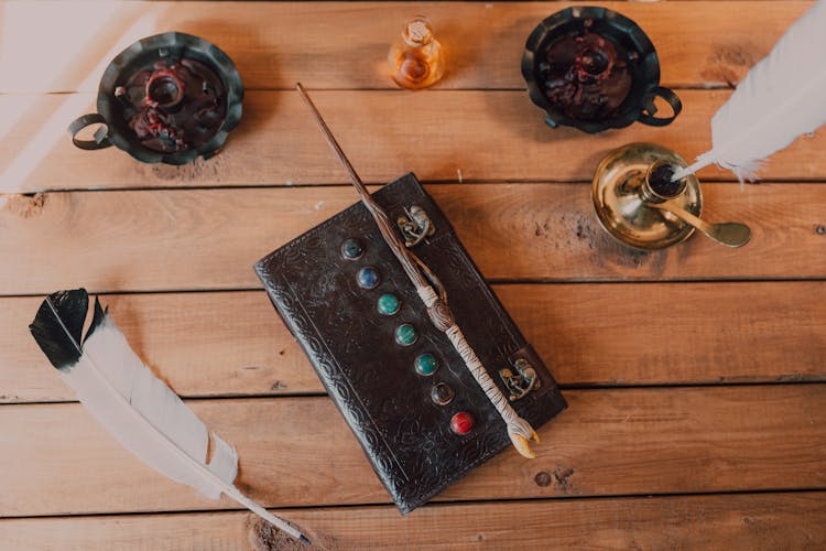 Close-Up Shot Of A Spell Book And A Wand