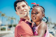 A Man in Red Shirt Carrying a Girl in Pink Dress