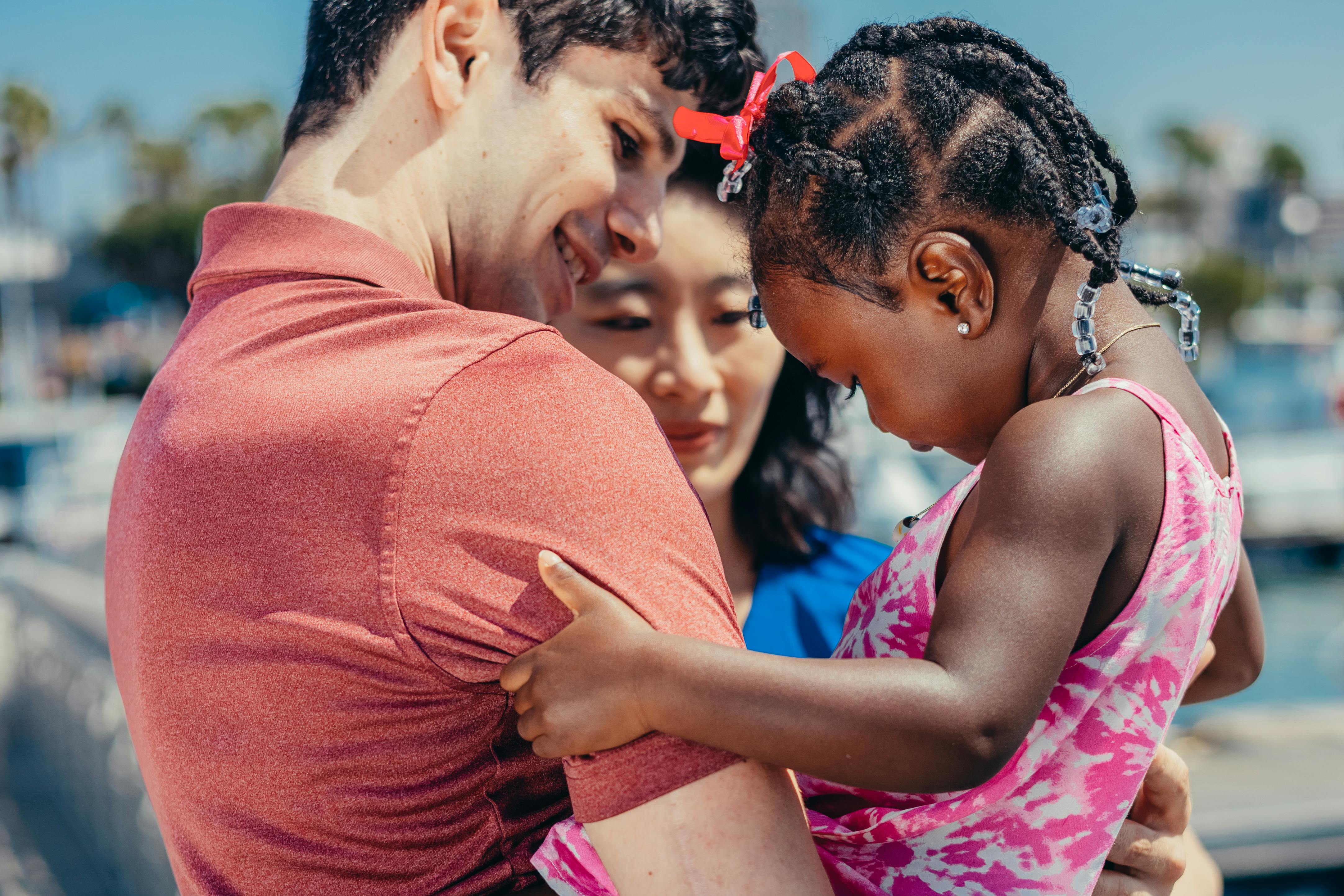 A joyful moment captured of a diverse family bonding outdoors on a bright summer day.