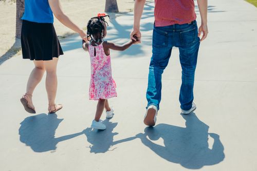 Free A diverse family enjoying a sunny day, holding hands and walking together. Stock Photo