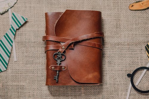 Free Leather Notebook Case with Key on Brown Textile Stock Photo