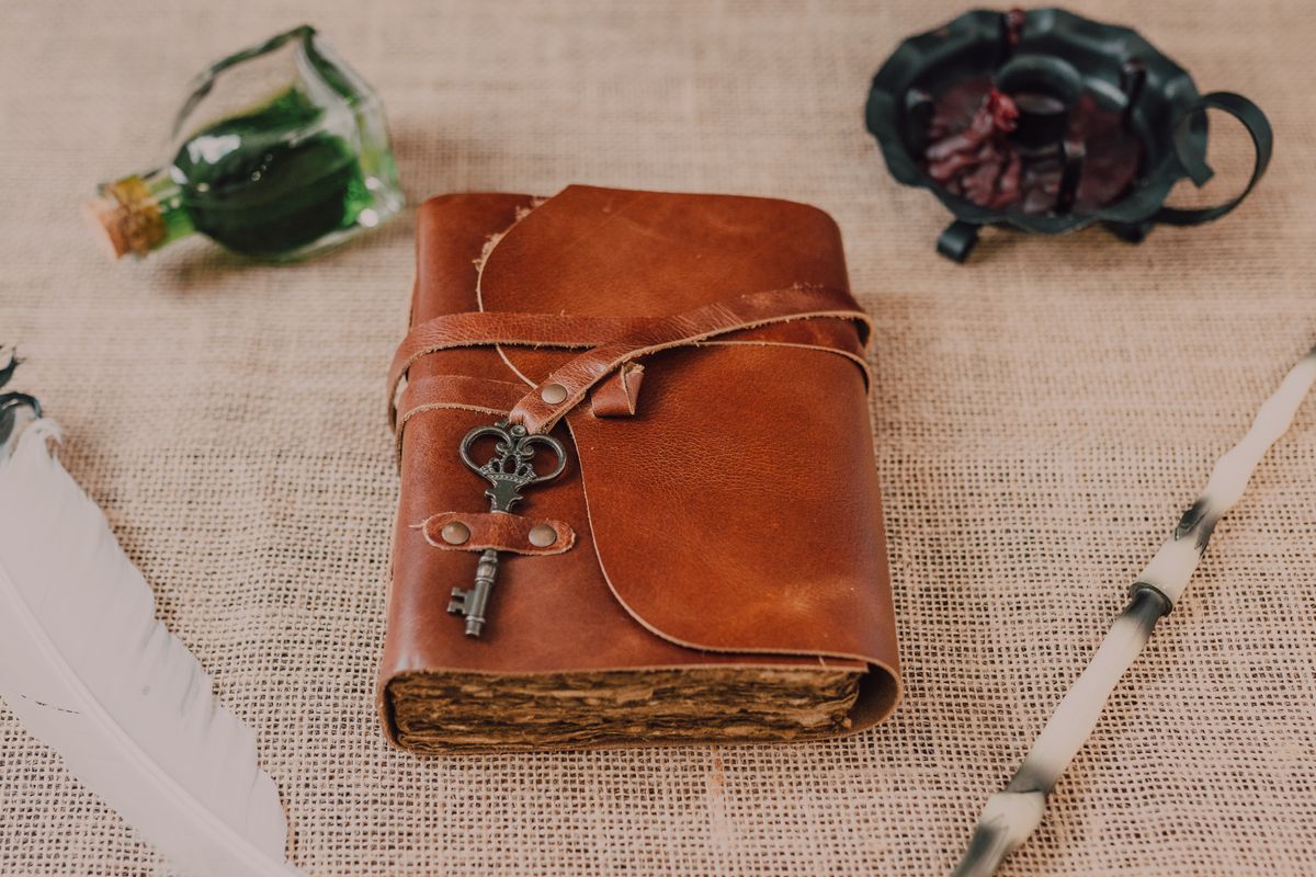 Livre ancien, clé, plume et accessoires de magie évoquant une énigme fantastique