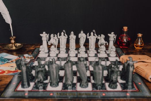 A vintage wizard-themed chess set with fantasy figurine pieces on a rustic table.