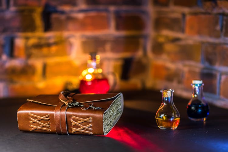 Close-Up Shot Of A Spell Book Beside Potions