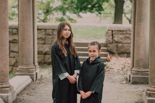 Girls Wearing Black Coats Standing near Concrete Column