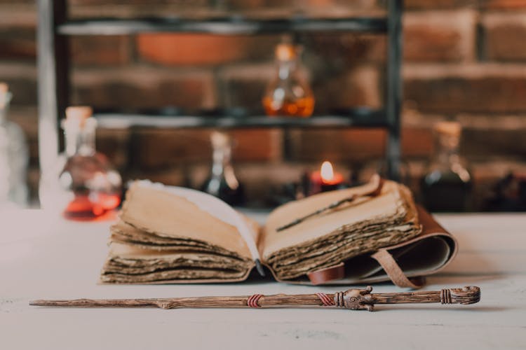 Close-Up Shot Of A Wand Beside A Spell Book