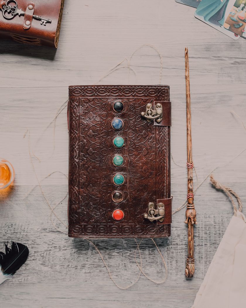 A leather-bound book with a wand lying beside it