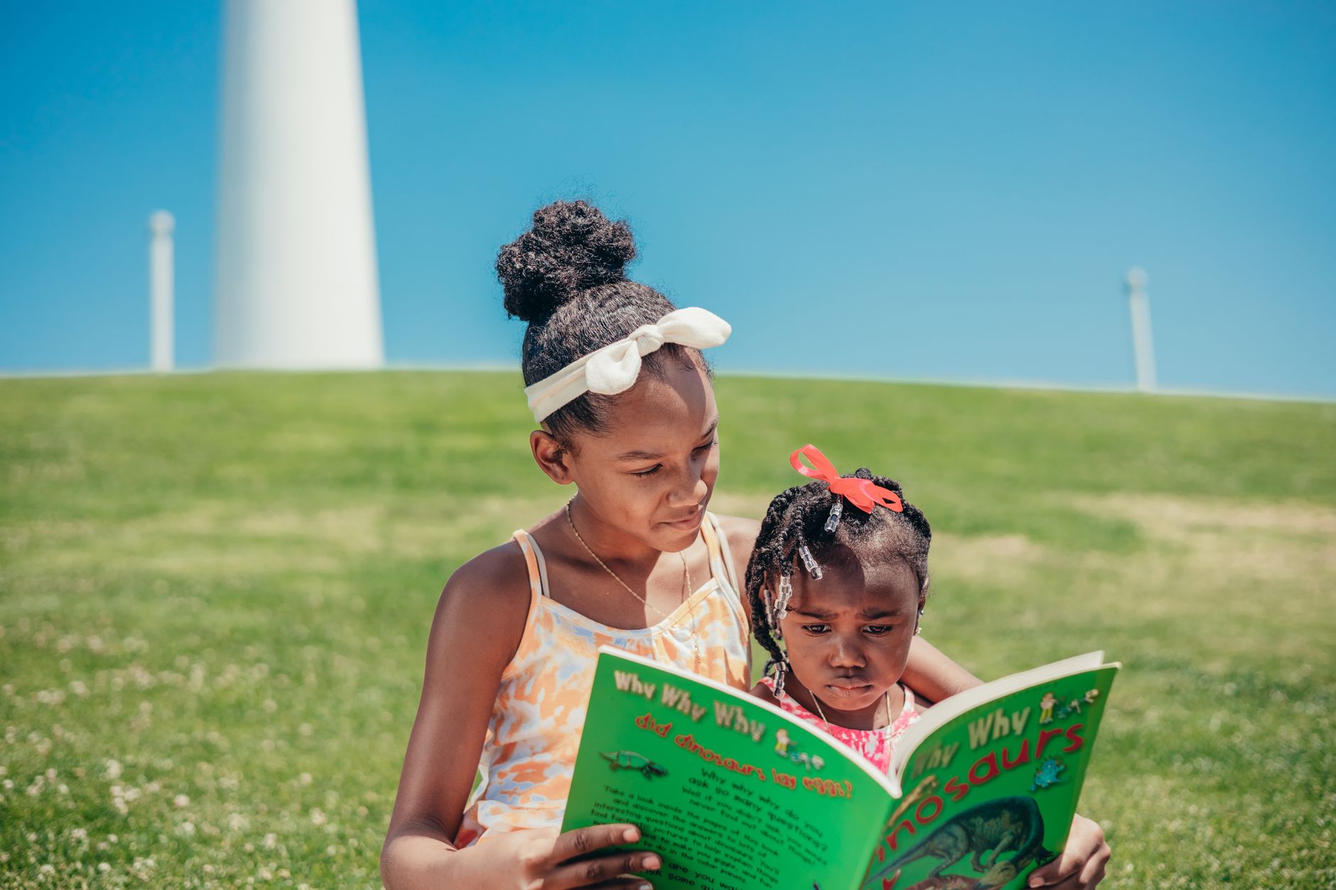 Two sisters reading together outdoors