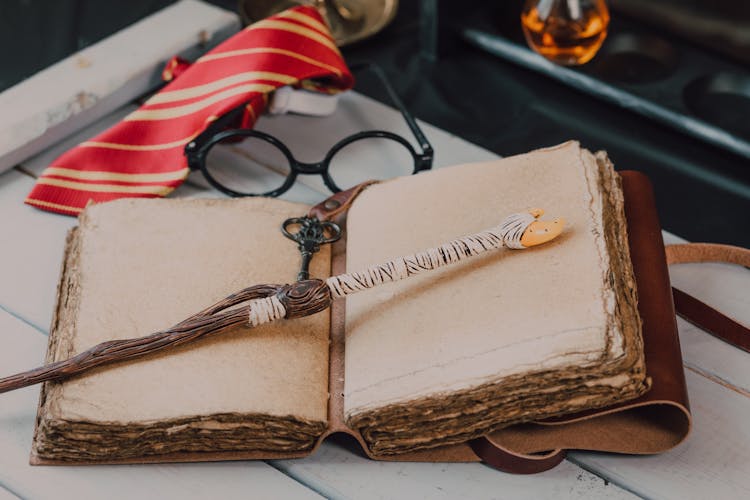 Close-Up Shot Of A Wand Beside A Spell Book