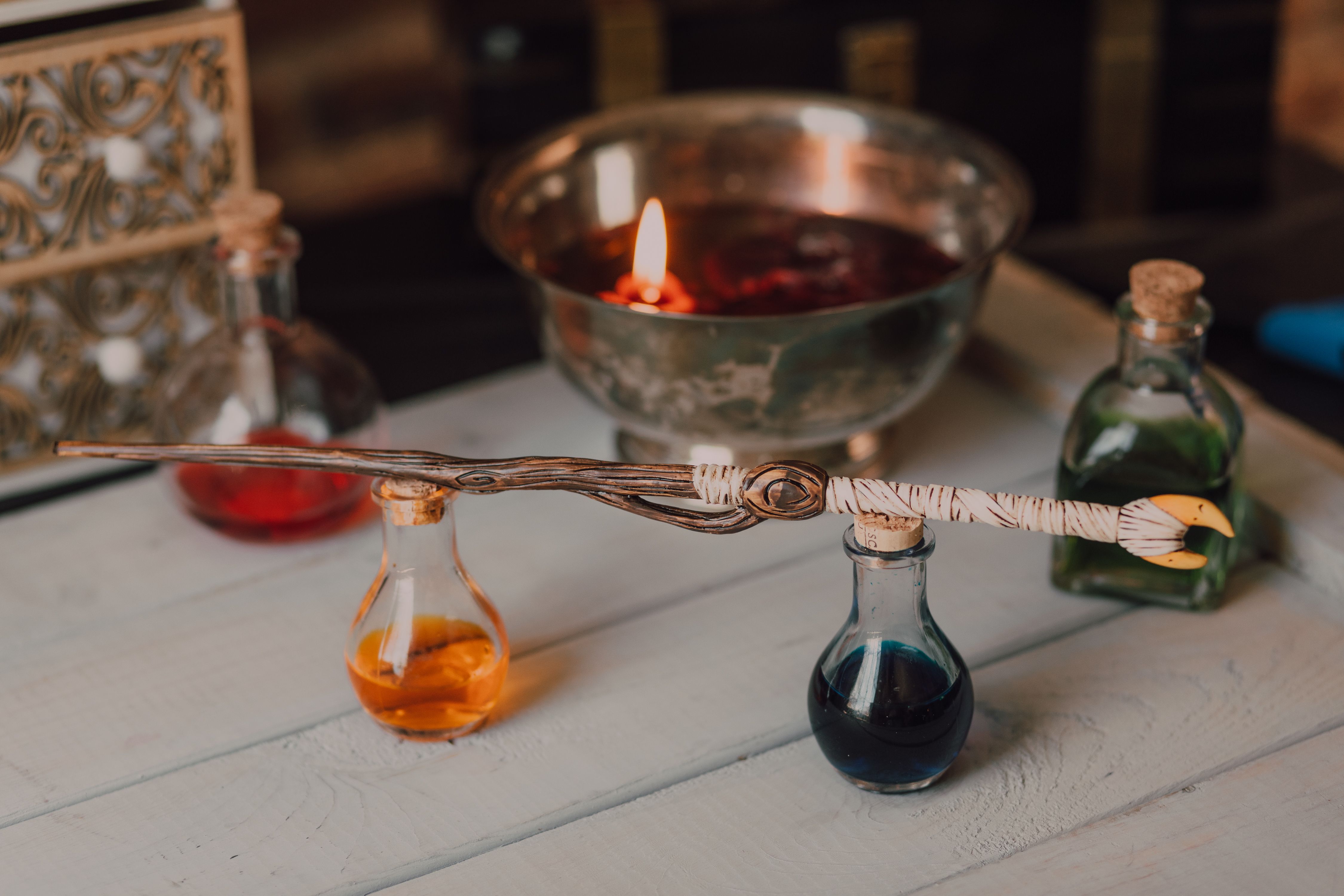 Présentation intrigante d'une baguette magique et de flacons de potions colorés dans un décor artistique.