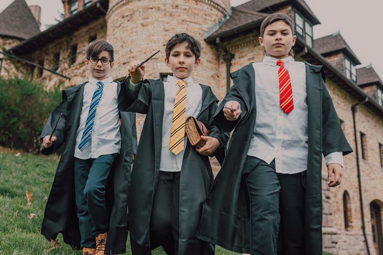 Three Boys In Black Robes Holding Wands