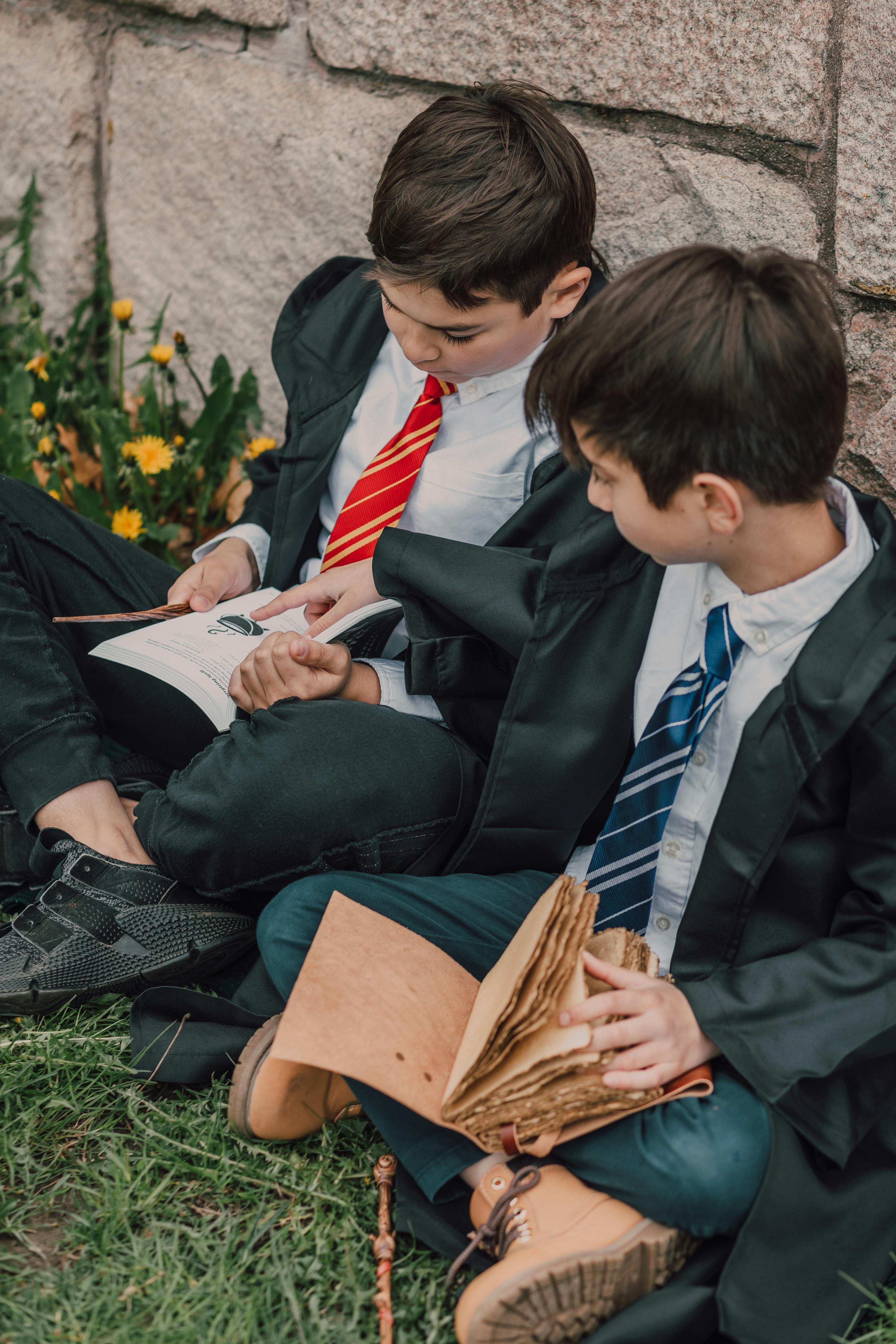 two boys in black robes reading