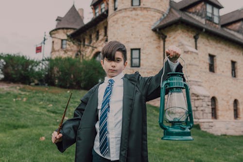 A Boy in Black Robe Holding a Lamp and a Wand