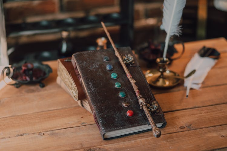 Close-Up Shot Of A Brown Spell Book And A Wand