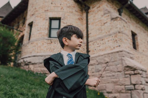 A Boy in Black Robe Holding a Wand