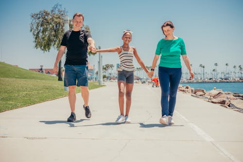 A Happy Family Holding Each Others Hands while Walking on the Bay