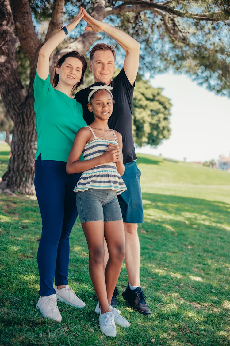 A Smiling Family Standing On Grass Field