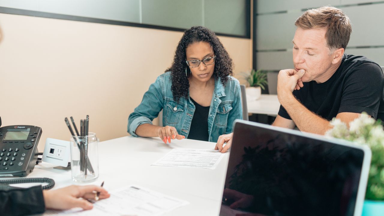 A couple discussing legal documents inside an office setting with an advisor.
