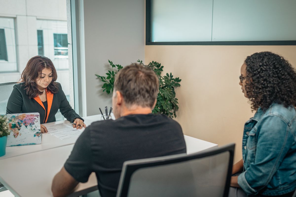 A professional consultant discussing creative work with clients at a desk