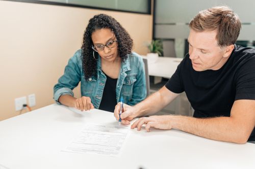 Free A couple working together to sign important legal documents at a desk in an office setting. Stock Photo