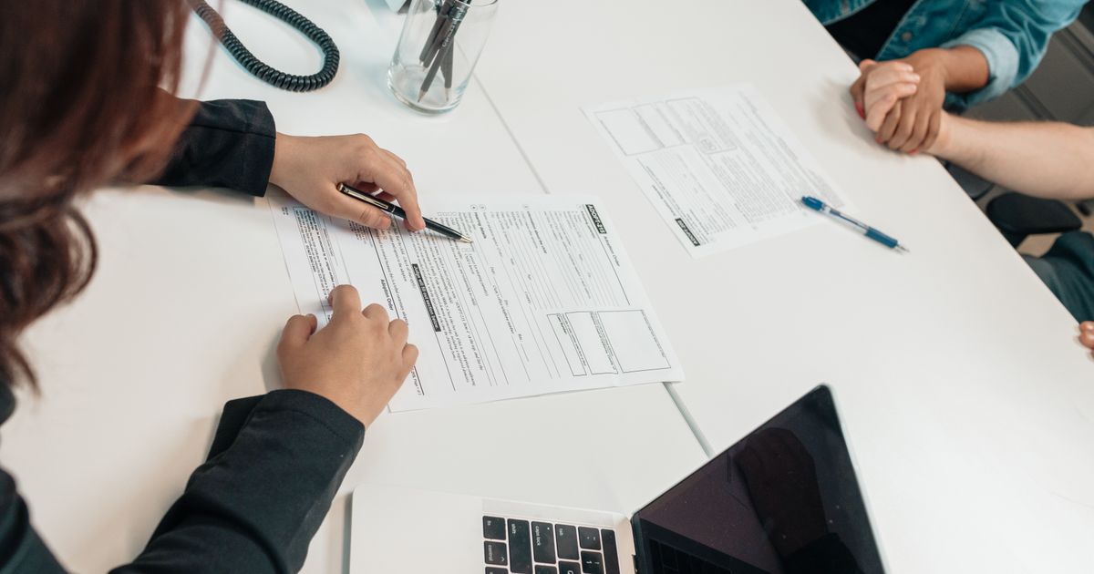 A legal advisor helping a small business owner fill out UK company registration forms in an office setting.