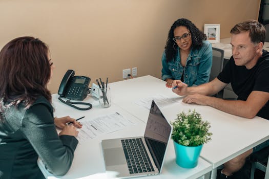 Diverse group engaged in a professional meeting around a desk in an office setting.